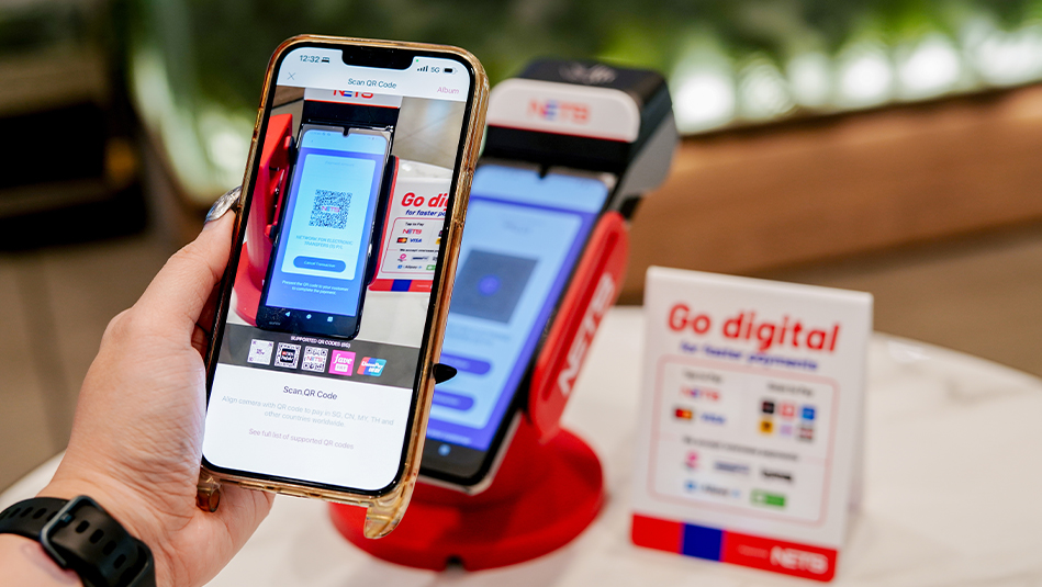 A person using her mobile phone to scan NETS QR code on the terminal
